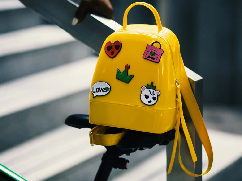 yellow-backpack-with-five-assorted-stickers-on-grey-metal-934673