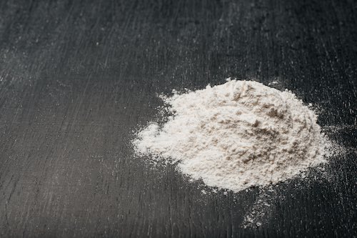 A hill of flour on a black background. Flour for baking