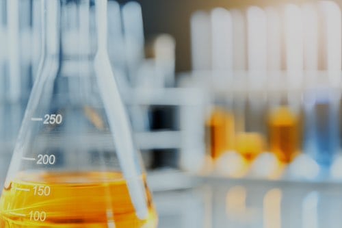 Lab flask glassware containing yellow chemical liquid in laboratory, lab research and development concept