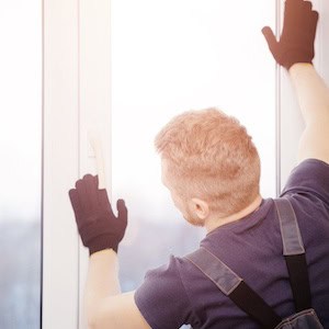Male builder installs and checks plastic windows in apartment house